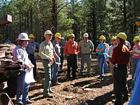 A group of men and women having a discussion at a biomass operation site.