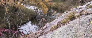 Granite outcrop above stream, with fall foliage