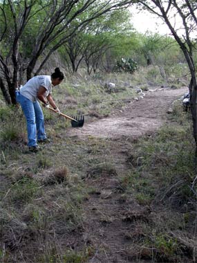 A volunteer from SWTJC levels the surface of the trail.