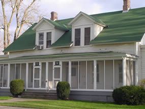 Duplex with two dormers, white walls, and green roof