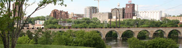 The Stone Arch Bridge crosses the Mississippi River with the Minneapolis skyline in the distance.