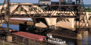 A barge going underneath a bridge.