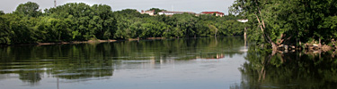 The Mississippi River reflects its wooded shorelines through the metropolitan Twin Cities area.