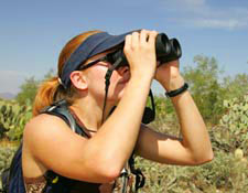 Photo of scholar looking through binoculars while at the Arizona-Sonora Desert Museum
