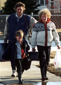 Woman with her children fleeing on foot with bags and suitcases along a sidewalk