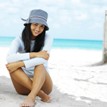 Young woman sitting on the beach smiling