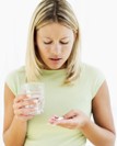 A woman holding a pill and a glass of water