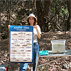 Heidi Blasius holding a fish poster and standing beside a container of fish