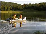 Two NPS staff in yellow safety suits on raft in lake.