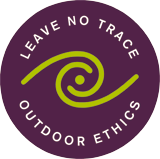 The logo for the Leave No Trace Center for Outdoor Ethics features those words in white on the dark purple background with a lime green swirl in the middle.