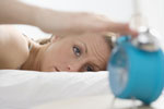 Photo of woman turning off her alarm clock