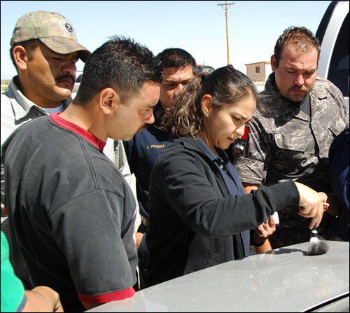 FBI Evidence Response Team Member Alma Ortega (center) show students at the Mexican American Liaison and Law Enforcement Training seminar hosted by the El Paso office recently how to dust a fingerprint.