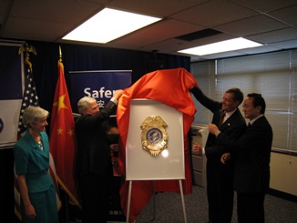 November  21, 2008 – U.S. Secretary of Health and Human Services (HHS) Michael O. Leavitt and the Honorable Andrew von Eschenbach, M.D.,  Commissioner of the HHS Food and Drug Administration (FDA), unveil the HHS/FDA shield at the ceremony for the opening of the  HHS/FDA office in Shanghai, in the People's Republic of China. Looking on are Beatrice Camp, the U.S. Consul General in Shanghai  (left), and Xu Jianguang, the Director of the Shanghai Municipal Health Bureau (right). (Photo Credit: Bill Steiger, HHS)