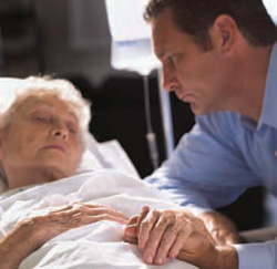 A photo of a man at an older woman's bedside
