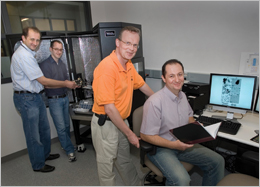 (From left) Dmytro Nykypanchuk and Mathew Maye load a sample into an atomic force
microscope, while Daniel van der Lelie and Oleg Gang review data at Brookhaven Lab's Center for Functional Nanomaterials.