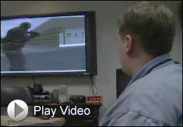 Photo of simulation team at work, with play button to the video page