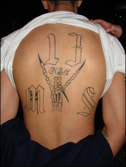 An MS-13 member arrested in the Houston salon robbery and extortion plot displays the gang affiliation tattooed on his back.