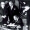Acheson, seated, signing treaty, President Truman and others watching (NATO)