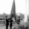 Men in military uniforms raising a flag, audience watching (NATO)