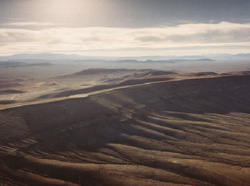 Aerial view of Yucca Mountain,�looking northwest, showing the desert environment. The proposed geologic repository would be located about 300 meters (1,000 feet) below the eastern slope of the mountain.