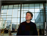 Man looks at windows lining lobby of building (AP Images)