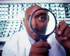 Photograph of a male doctor looking through a magnifying glass