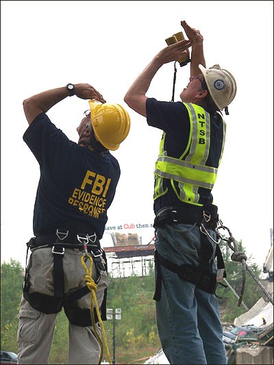 An FBI ERT member and NTSB official survey the damage at the collapsed bridge site.