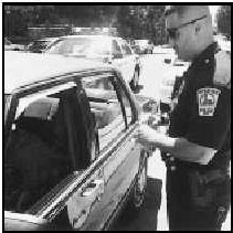 Photograph of a police officer standing next to  a car