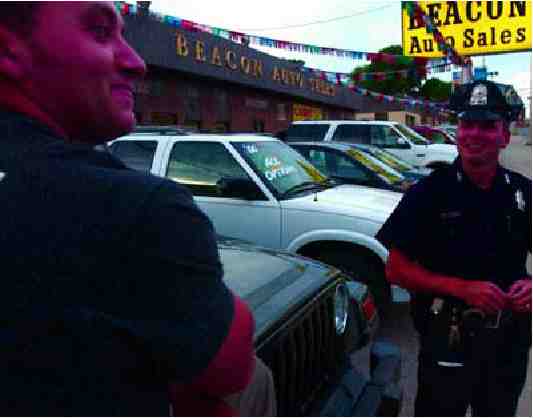 Photograph of police officer talking to a car salesman