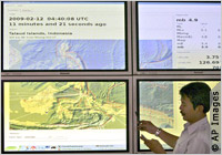 Man standing by large screens with earthquake data (AP Images)