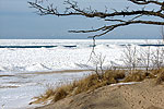 sandy beach in the foreground and lots of ice covering a large lake