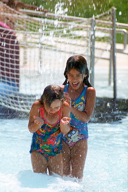 two girls splashing water in pool