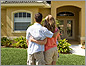 Photo of the backs of a man and woman standing arm-in-arm looking at a home.