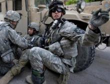 A US soldier gestures to fellow soldiers as he tends to a comrade overcome by shock after an Improvised Explosive Device detonated on his vehicle during a patrol in Baghdad, Iraq, on 19 March 2007 (Image: David Furst/AFP/Getty)