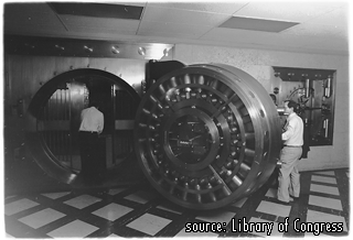 Picture of a person holding the door open to a Bank vault