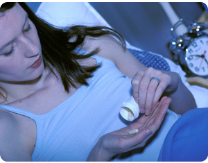 Photo of woman in bed taking sleeping pills.