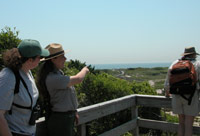 Ranger on overlook points to ocean in the distance.