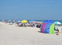 Crowds on beach with colorful umbrellas.