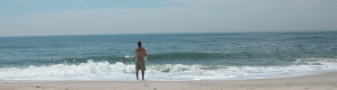 Lone fisherman on the beach with line in the surf.