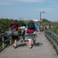 Group of backpackers walk down boardwalk through tall grasses.