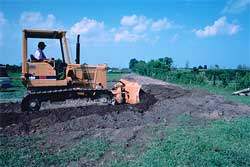 A bulldozer pushing soil to lower a levee