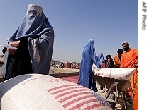 Afghan women leave the World Food Programme (WFP) food distribution center after receiving food aid in Kabul, 9 Mar 2008