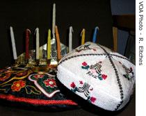 An Islamic cap and embroidered pillow with a Jewish Hanukkah menorah make a colorful montage