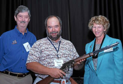 Photograph: Dave Zalunardo poses with Rocky Evans and Gail Tunberg.  Dave is holding his gun.