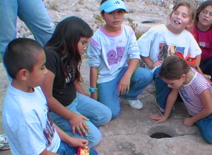 School group looking at a prehistoric mortar hole