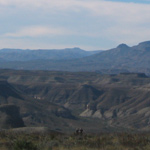 Two hikers dwarfed by the landscape of the Mesa de Anguila