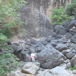 A visitor sits at the base of the Pine Canyon pour-off