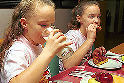 Dos niñas comiendo comida sana. Enlace a la información en inglés sobre la foto