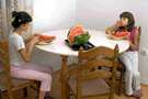 Image of two little girls eating watermelon at the dining room table