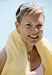 Smiling older woman, towel around neck, who has just finished her swimming workout.